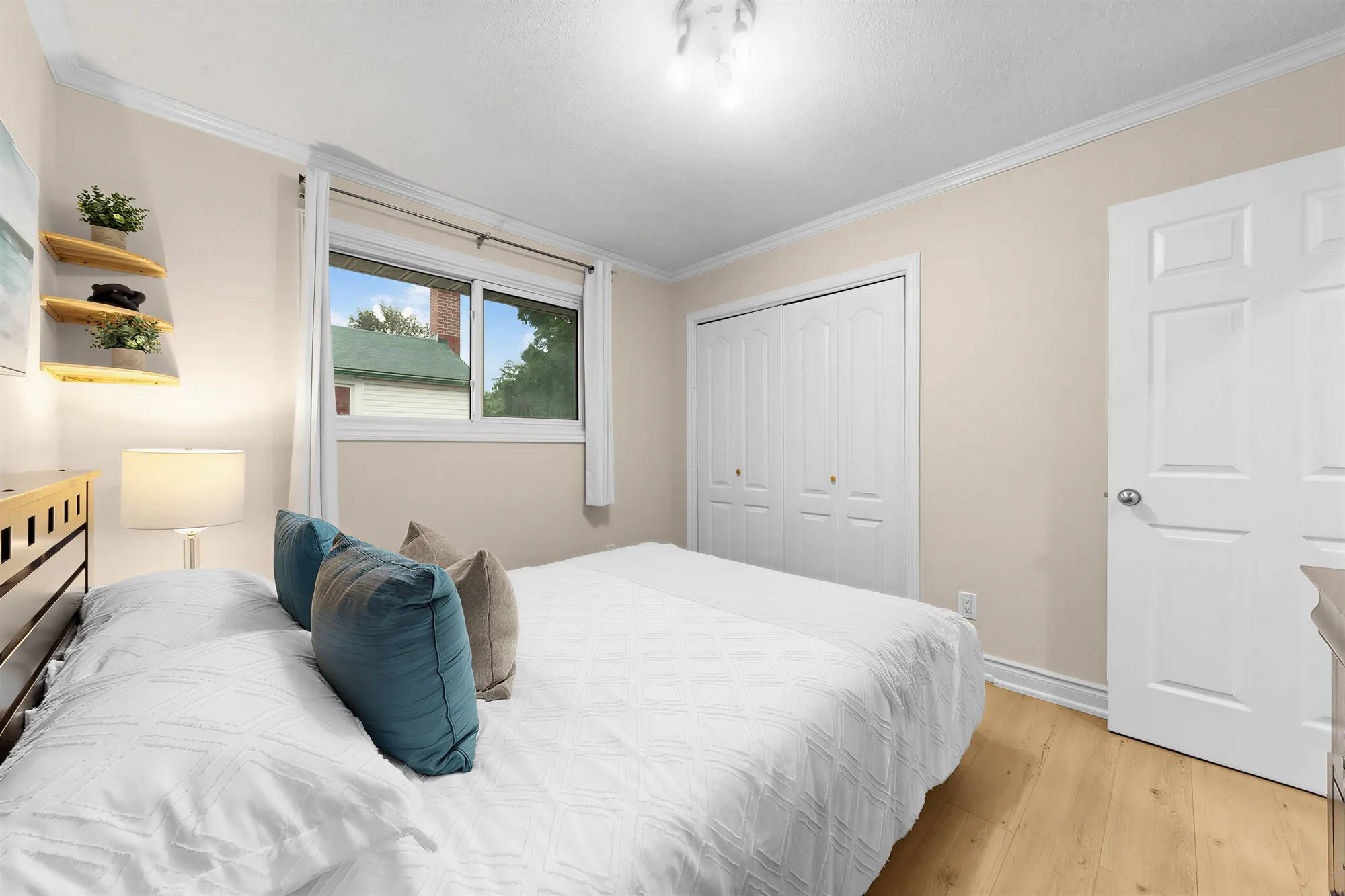 The same bedroom toward the closet with white folding doors and the door, the window at the left