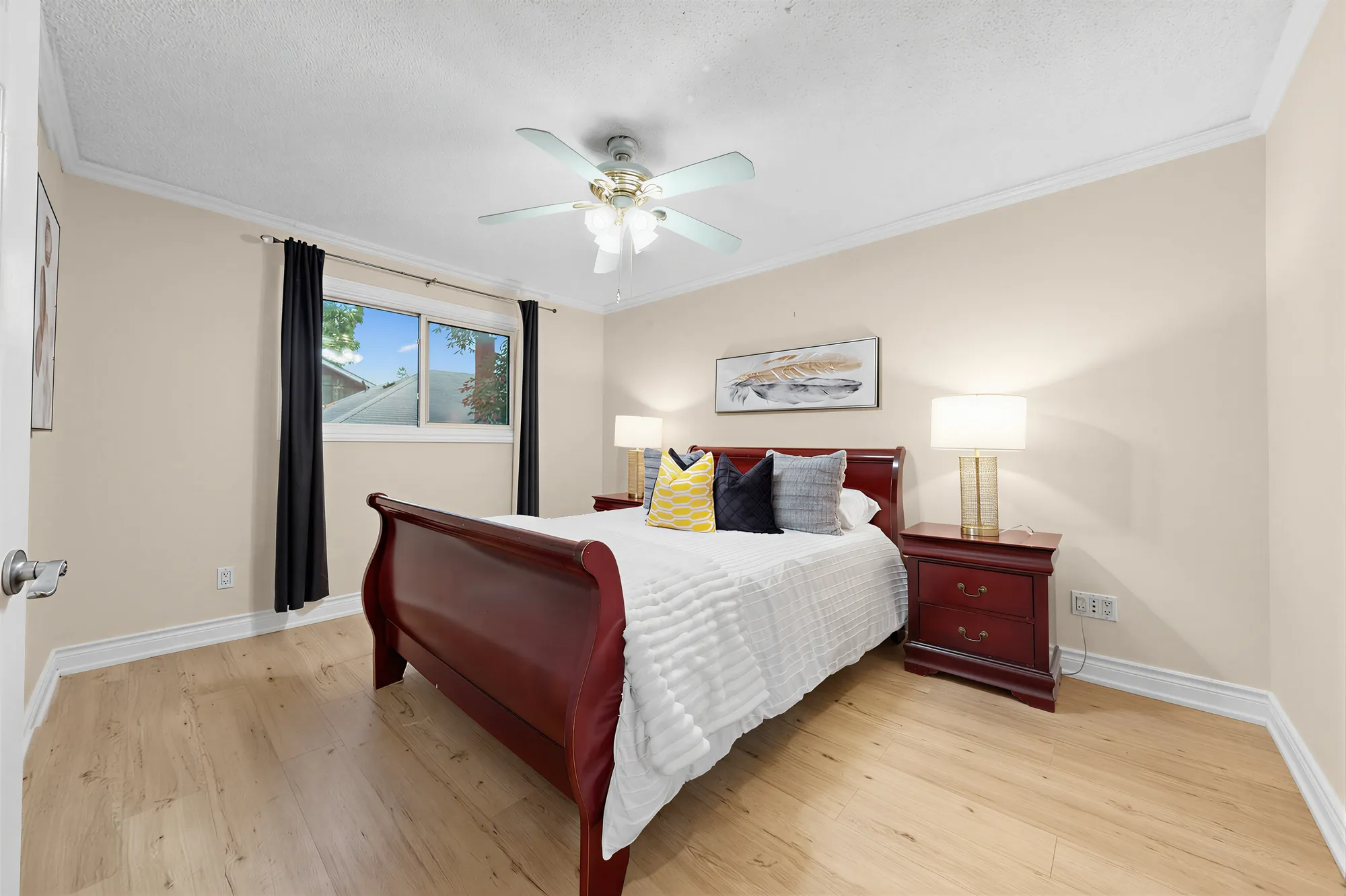 The same bedroom toward its window, the sleigh bed and a night table with a lamp, dark curtains