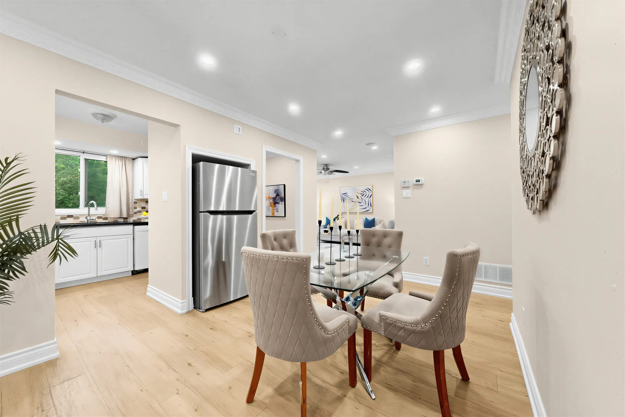 The dining table toward the kitchen, the stainless fridge and a window