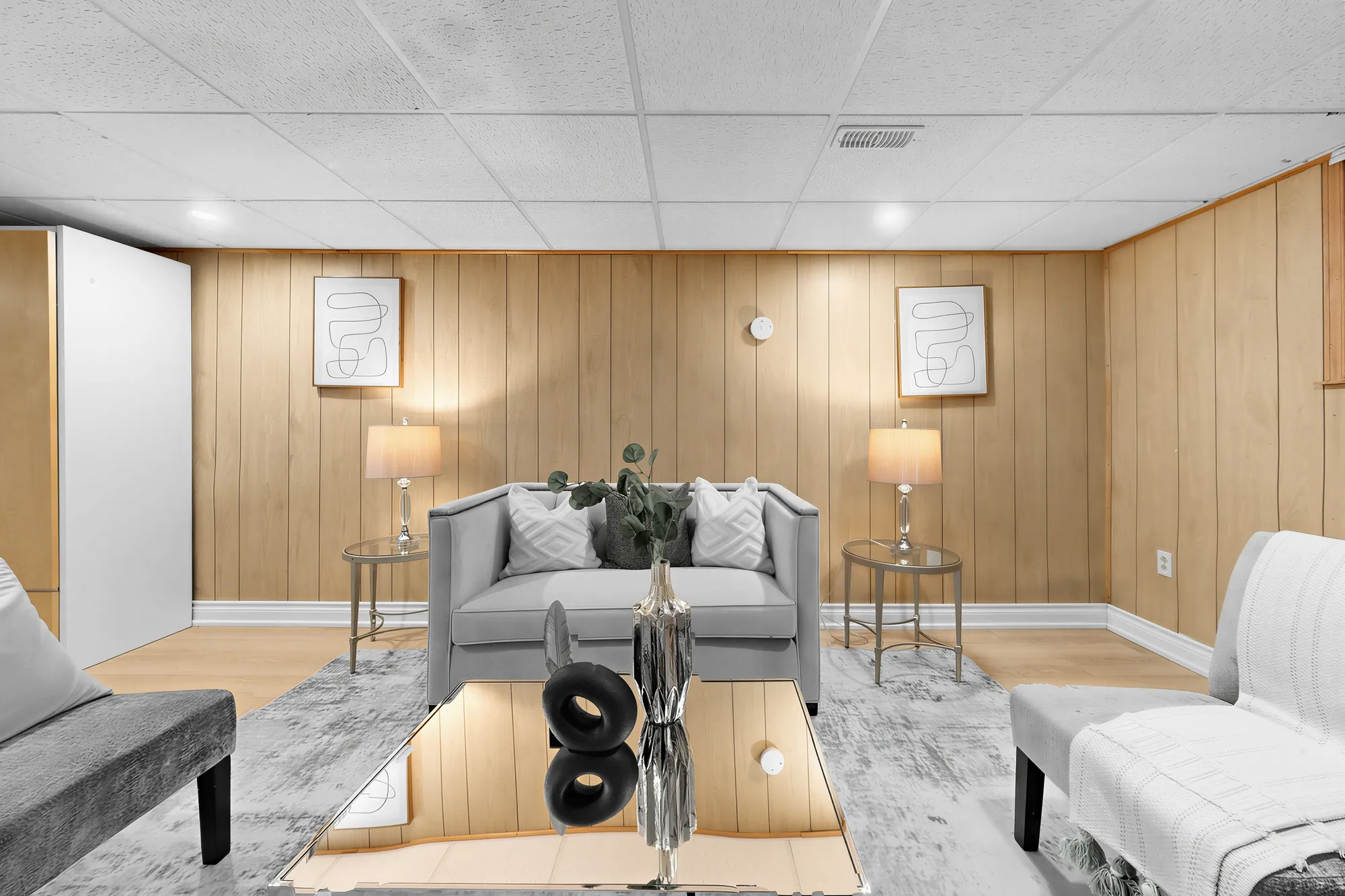 The family room toward the panelled wall: a sofa between two lamps, a coffee table and armchairs