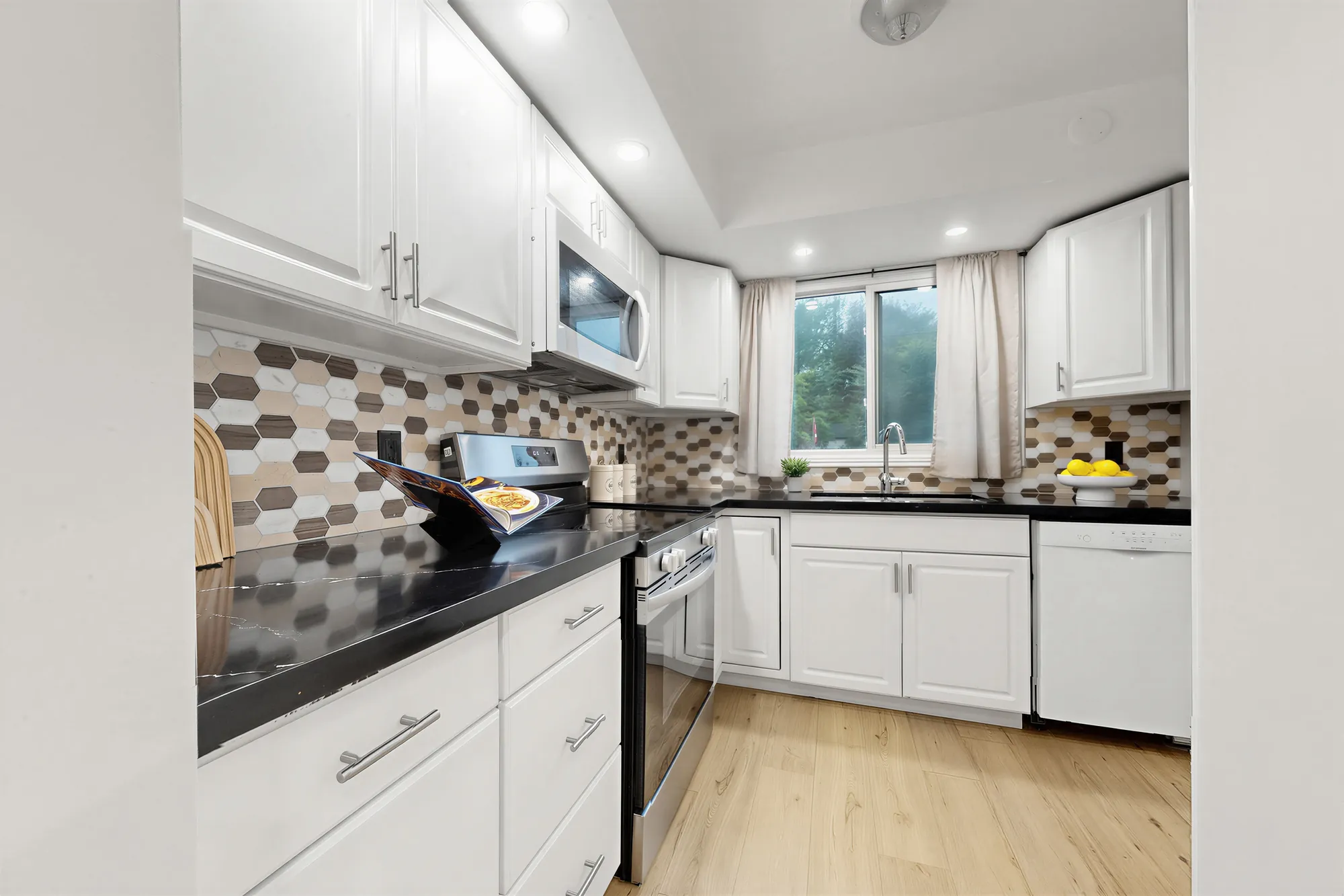 Along the kitchen counter to the window over the sink, white cabinets above and below