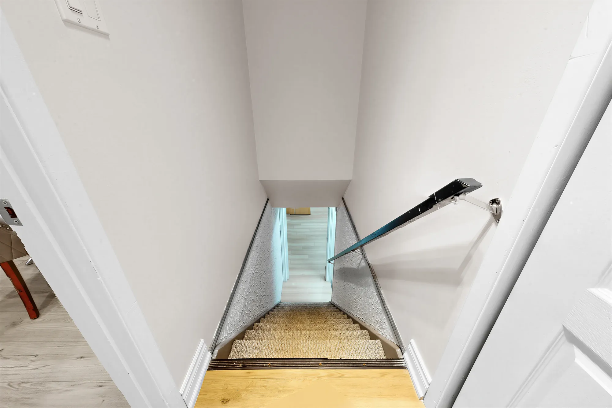 Looking down the stair to the lower floor, a handrail on the wall